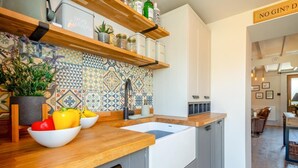 A modern kitchen with a wooden countertop, a sink, and a backsplash with geometric patterns. There are cabinets above the countertop and a sign that reads 'NO GIN? D'. - 2 Bed in Rhydyclafdy (oc-b44972) (Buan)