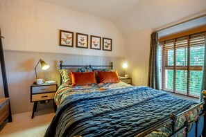 Ein Schlafzimmer mit einem Bett, zwei Nachttischen, einem Fenster mit Jalousien und einem an der Wand hängenden Kunstwerk.