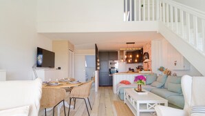 Uma sala de estar moderna com área de jantar, cozinha e escada.