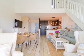 A modern living room with a dining area, kitchen, and staircase. - Le 21 des dunes - La mer comme horizon (Saint-Jean-de-la-Rivière)
