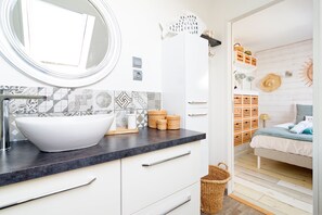 A modern bathroom with a white sink, patterned tiles, and a mirror. - Le 21 des dunes - La mer comme horizon (Saint-Jean-de-la-Rivière)