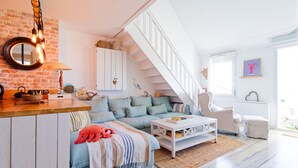 Um espaço de estar tipo loft com escada, área de cozinha e um espaço de estar aconchegante.