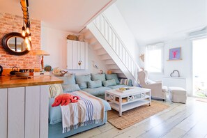 A loft-style living space with a staircase, a kitchen area, and a cozy seating area. - Le 21 des dunes - La mer comme horizon (Saint-Jean-de-la-Rivière)