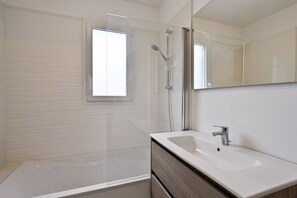 A modern bathroom with a glass-enclosed shower, a white sink, and a large mirror. - Ti Ruz - À 200 m de la plage (Pénestin)