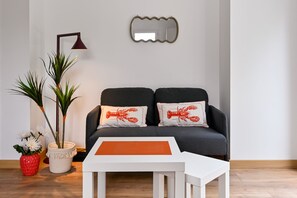 A living room with a dark sofa, two lobster pillows, a white coffee table, a floor lamp, and a mirror on the wall. - Ti Ruz - À 200 m de la plage (Pénestin)