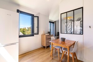 Eine kompakte Küche mit Essbereich, einem Holztisch, weißen Stühlen, einem Schrank und einem Fenster mit Blick.
