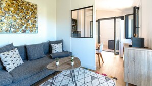 Ett modernt vardagsrum med en grå soffa, ett runt soffbord och en stor, abstrakt tavla på väggen.
