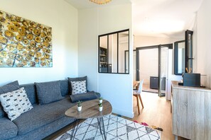 Ein modernes Wohnzimmer mit einem grauen Sofa, einem runden Couchtisch und einem großen abstrakten Gemälde an der Wand.