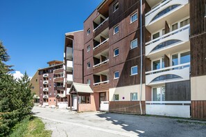 A multi-story residential building with balconies, a covered entrance, and a gravel driveway. - Le Sommet 503 - Station de ski accessible à pied (Huez)