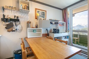 A kitchen with a wooden table, chairs, and various kitchen utensils and appliances. - Le Sommet 503 - Station de ski accessible à pied (Huez)