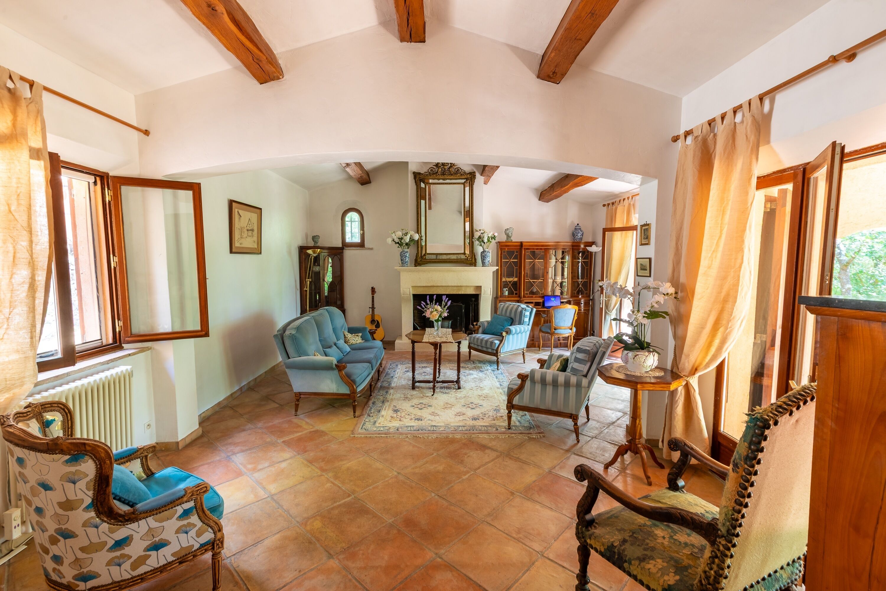 Un salón espacioso con chimenea, varias opciones de asientos y vistas al exterior.