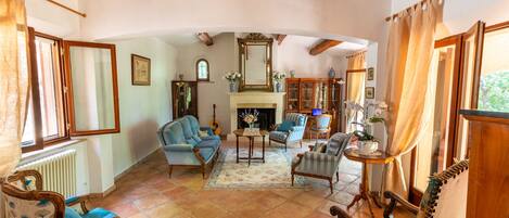 Un salón espacioso con chimenea, varias opciones de asientos y vistas al exterior.
