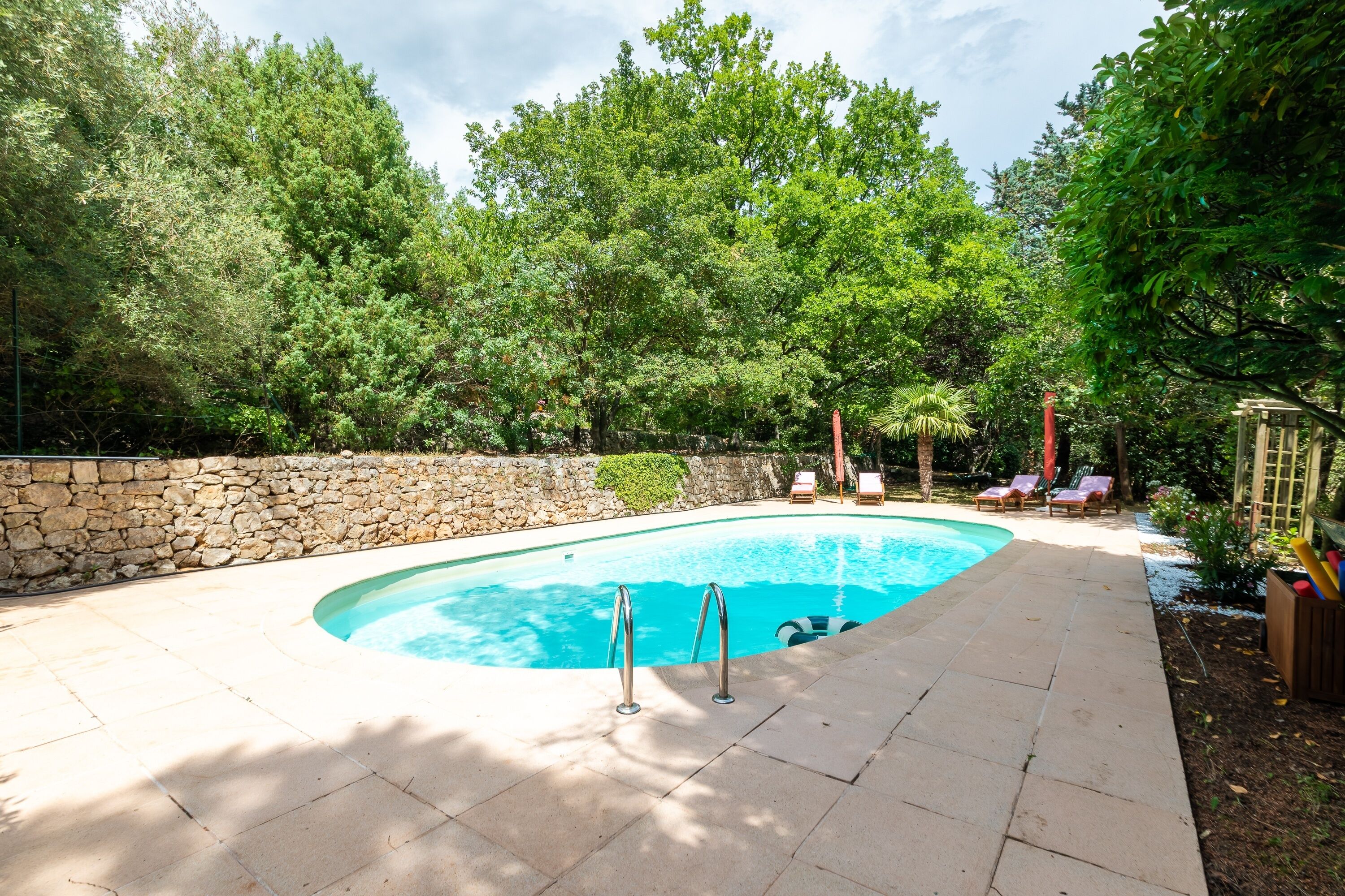 Ein Pool mit einer Steinmauer und Liegestühlen.