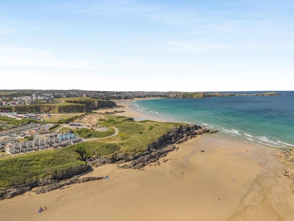 En kystby med en sandstrand, en klippefyldt kystlinje og en blanding af boliger og erhvervsbygninger.