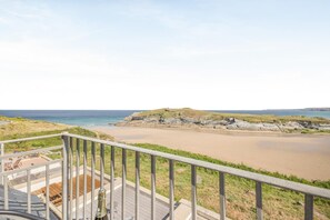 Blick auf die Küste vom Balkon mit Geländer, einen Sandstrand und Felsformationen.
