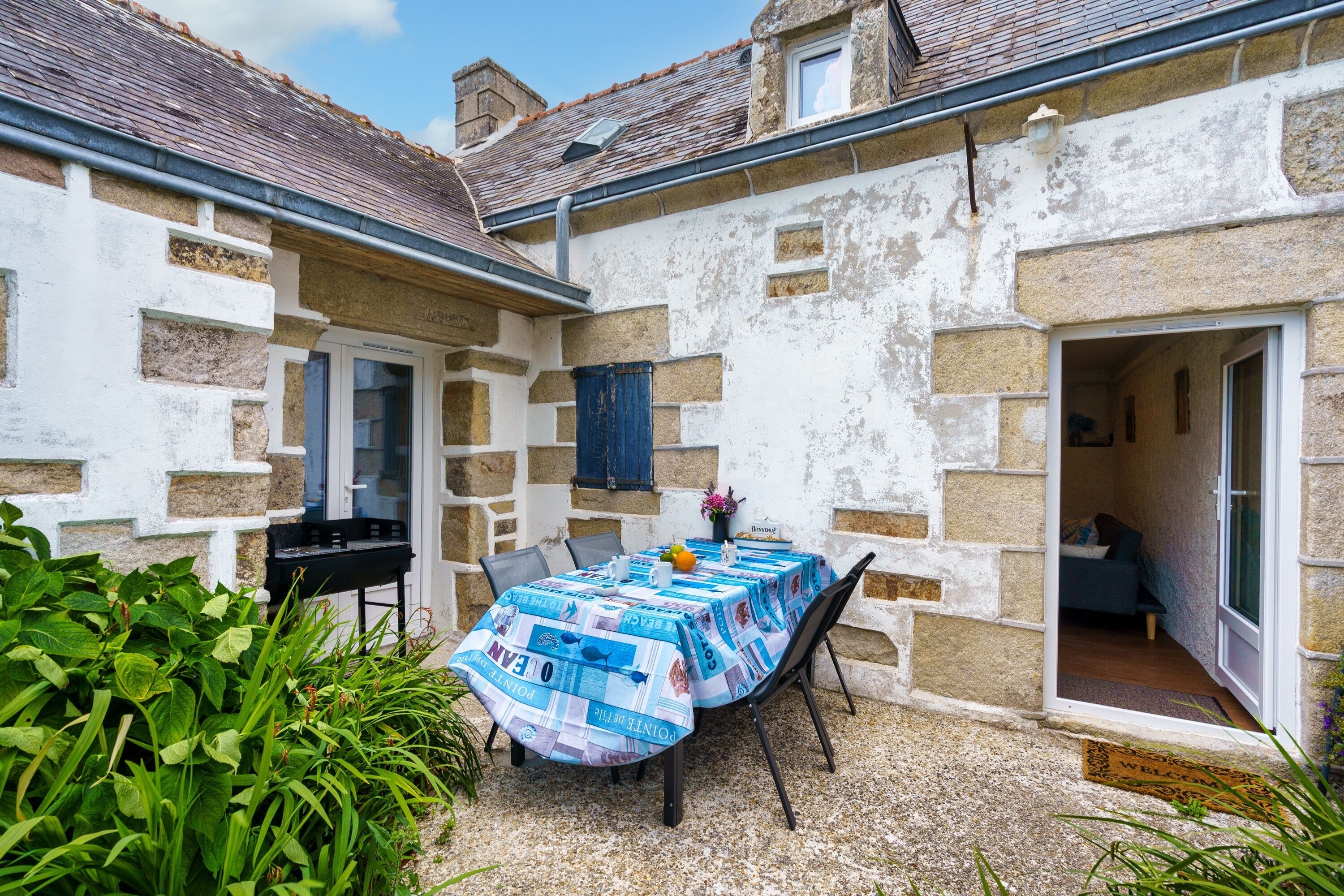 A small courtyard with a table set for dining, a door leading to a room, and a small garden area.