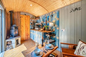 Une cuisine chaleureuse avec un poêle à bois, des meubles en bois et un coin repas avec une table mise pour deux personnes.