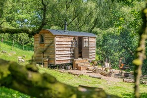 A rustic wooden cabin with a chimney, surrounded by lush greenery. - 1 Bed in Langdale End (oc-h44909) (Allerston)