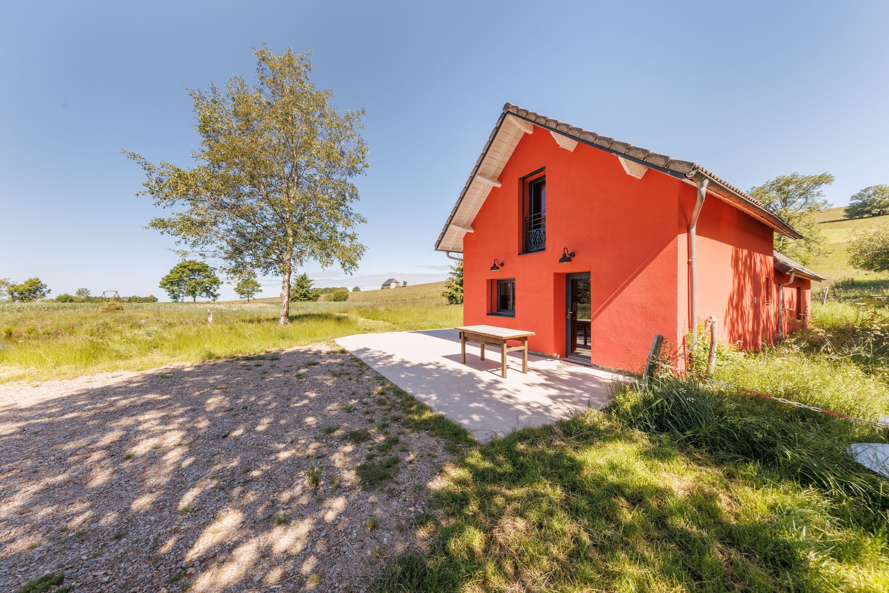 A red building with a sloped roof, a door, and a window.