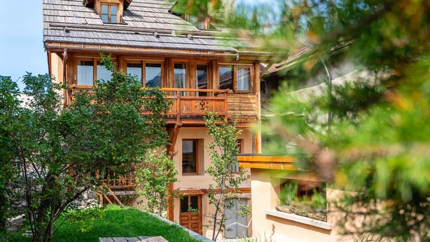 Una casa in legno con un balcone, una porta e una finestra.