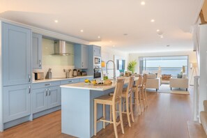 Une cuisine moderne dotée d’un îlot central, de chaises en bois et d’un coin repas offrant une vue agréable.