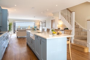 A modern kitchen with a central island, wooden flooring, and a view to the outside. - 3 Bed in Beadnell (oc-b41416) (Beadnell)