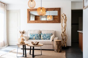 A living room with a sofa, two side tables, a mirror, and a wooden sculpture. - Orezza - Four Bedroom Chalet, Sleeps 10 (La Salle-les-Alpes)