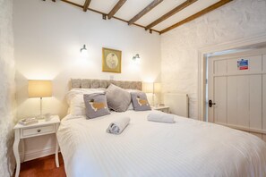 A bedroom with a bed, two bedside tables, a nightstand, a radiator, and a door with a fire safety sign. - 2 Bed in Betws Garmon (oc-b45268) (Betws Garmon)