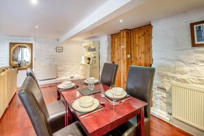 A dining area with a wooden table set for four, surrounded by chairs. - 2 Bed in Betws Garmon (oc-b45268) (Betws Garmon)