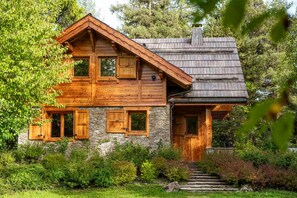 Eine Holzhütte mit steinernen Fundamenten, Holzläden und einem Schornstein.