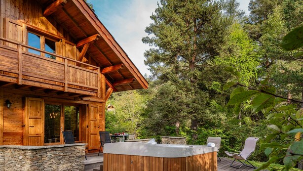 A wooden cabin with a hot tub, stone foundation, and a deck. - Trancoulette - Five Bedroom Chalet, Sleeps 12 (La Salle-les-Alpes)
