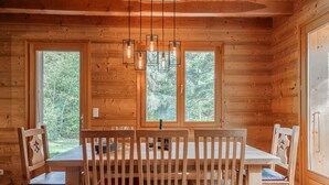 A wooden cabin interior with a dining table, chairs, and a hanging light fixture. - Trancoulette - Five Bedroom Chalet, Sleeps 12 (La Salle-les-Alpes)