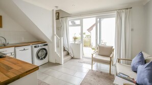 A kitchen with a washing machine, a wooden counter, and a chair.