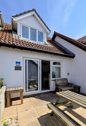 A two-story house with a tiled roof, a sliding glass door, and a wooden bench. - 2 Bed in Weymouth (oc-s42796) (Weymouth)