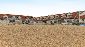 A row of houses with a pebbled beach in the foreground.