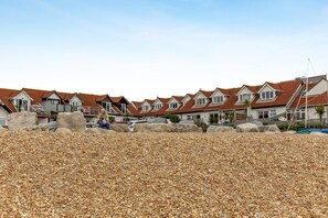 A row of houses with a pebbled beach in the foreground.