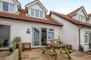 A residential property with a patio, a wooden table, and a sliding glass door.