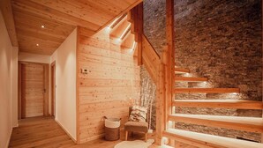 Un interno in legno con una scala, una porta e un muro in pietra.