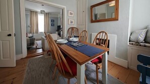A dining area with a wooden table, chairs, and a rug. There are doors leading to other rooms.