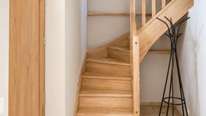 A wooden staircase with a handrail, a door, and a tripod lamp. - Le Logis Bleu: A Haven of Peace in Occitan Tuscany (Puybegon)