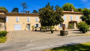 A traditional building with a stone-paved courtyard, potted plants, and a clear blue sky. - Le Logis Bleu: A Haven of Peace in Occitan Tuscany (Puybegon)