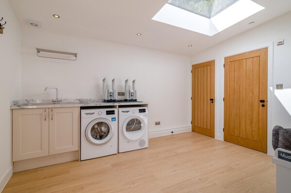 A laundry room with two washing machines, a sink, and a skylight.