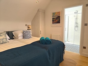 A bedroom with a bed, a wardrobe, a shower, and a painting.