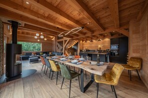 A modern log cabin interior with a dining area, kitchen, and a staircase.