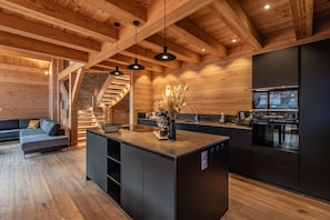 A modern kitchen with wooden beams, a central island, and a built-in oven.
