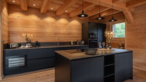 Una cucina moderna con pareti in legno, mobili neri e luci a sospensione.