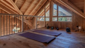 A spacious attic room with wooden beams, large windows, and exercise mats. - Chalet Le Refuge - Five Bedroom House, Sleeps 14 (La Salle-les-Alpes)