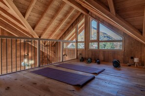 A spacious attic room with wooden beams, large windows, and exercise mats. - Chalet Le Refuge - Five Bedroom House, Sleeps 14 (La Salle-les-Alpes)