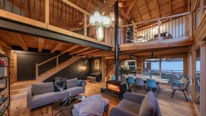 A spacious loft-style living area with a fireplace, seating, and a dining area with a view. - Chalet Le Refuge - Five Bedroom House, Sleeps 14 (La Salle-les-Alpes)