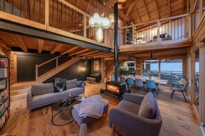 A spacious loft-style living area with a fireplace, seating, and a dining area with a view.
